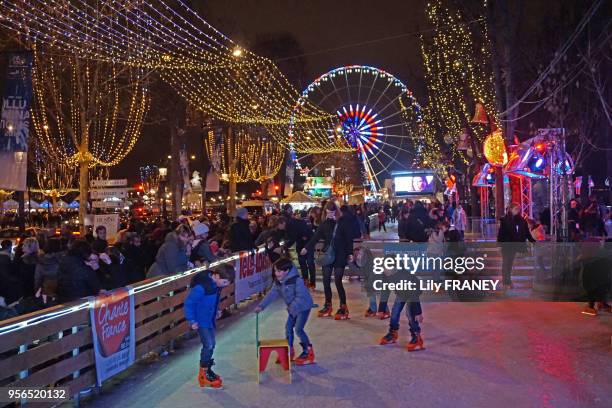 Enfants sur la patinoire au village de Noël des Champs Elysées et grande roue en bleu blanc rouge le 12 décembre 2015, Paris, France.