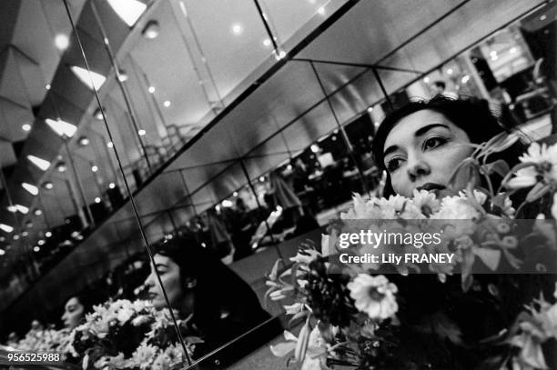 Jeune femme avec un bouquet de fleurs dans un café parisien, balade poétique Paris, France. Photo extraite d'une exposition inspirée du poème...