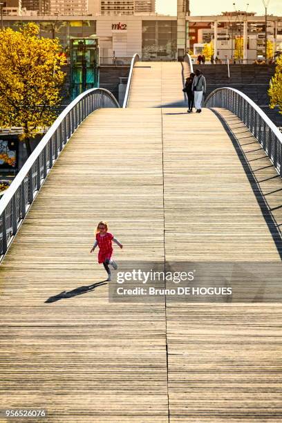 Une petite fille habillée en rouge courant sur la Passerelle Simone-de-Beauvoir, 2 mai 2016, Paris, France.