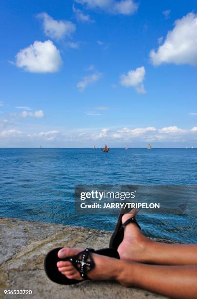 Jambes d'une femme allongée sur la digue et chaussées de tongs, 9 aout 2014, La Flotte-en-Ré, Ile de Ré, Charente-Maritime, France.