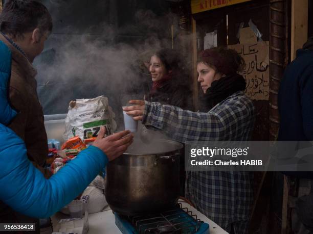Jeunes femmes bénévoles servant des boissons chaudes et des cookies, camp de réfugiés, le 16 février 2016, Dunkerque, France.