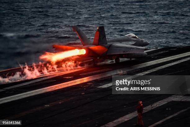 Crew member of the 330 meters US navy aircraft carrier Harry S. Truman gestures as a pilot of an F18 Hornet fighter jet waits to take off on eastern...