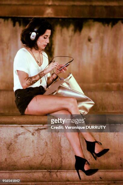 Jeune femme écoutant de la musique avec son téléphone portable, Plaza de la Virgen, vieille ville de Valence, 15 juillet 2016, Espagne.