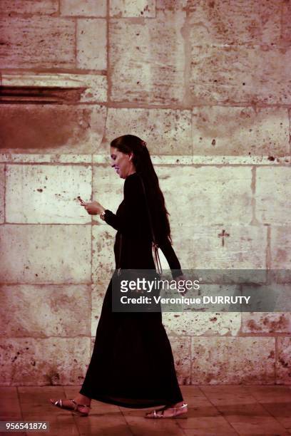 Jeune femme consultant son téléphone portable tout en marchant, vieille ville de Valence, 15 juillet 2016, Espagne.