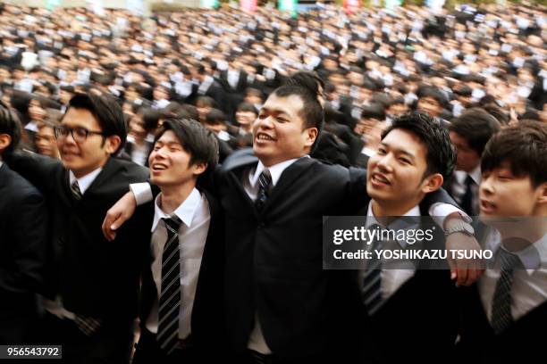 Etudiants japonais en costumes sombres se tenant par les épaules lors du coup d'envoi pour la recherche d'emploi, le 1er mars 2017 à Tokyo, Japon....