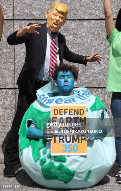 Des membres des assocoiations de défense de l'environnement Greenpeace et 350.org protestent contre la décision du président américain Donald Trump...