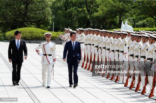Japanese Prime Minister Shinzo Abe , accompanied by Defense Minister Itsunori Onodera reviews the honor guards at the Defense Ministry in Tokyo on...