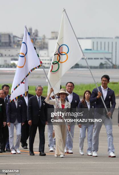 Tokyo Governor Yuriko Koike and Olympic athlete Keisuke Ushiro carry the Olympic flag and Japan Olympic Committee flag upon their arrival at the...