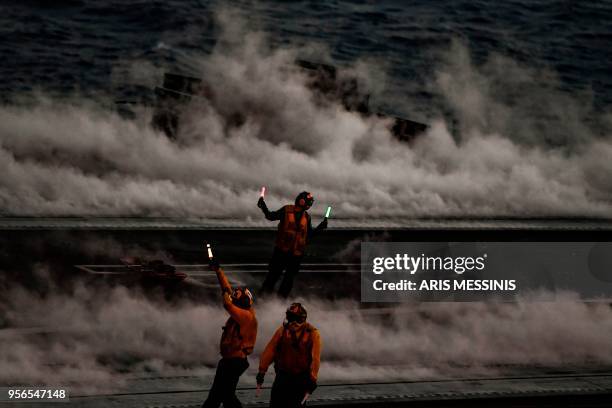 Crew members stand on the deck of the 330 meters US navy aircraft carrier Harry S. Truman after an F18 Hornet fighter jet takes off on eastern...