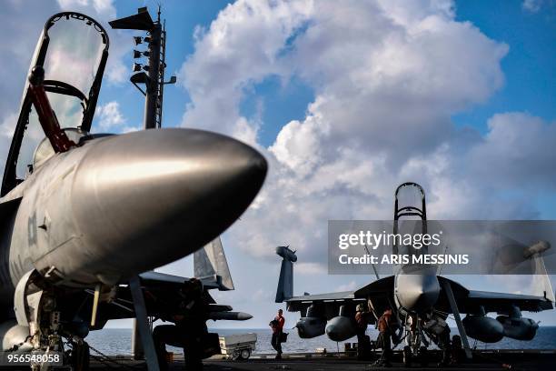 Crew members of US aircraft carrier USS Harry S Truman work on fighter jets on the flight deck of the ship in the eastern Mediterranean Sea on May 8,...