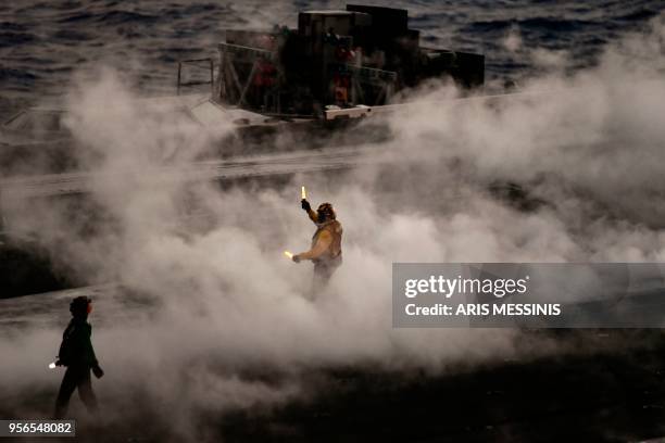 Crew member of US aircraft carrier USS Harry S Truman reacts after the takeoff of an F18 Hornet fighter jet from the flight deck of the ship in the...