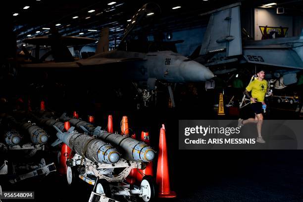 Crew member of US aircraft carrier USS Harry S Truman runs past F18 Hornet fighter jets and missiles on the hangar deck of the ship in the eastern...