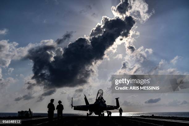 Crew members of US aircraft carrier USS Harry S Truman stand beside an F18 Hornet fighter jet on the flight deck of the ship in the eastern...