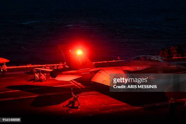 Crew member gestures as a F18 Hornet fighter jet waits to take off from the deck of the 330 meters US navy aircraft carrier the USS Harry S. Truman...