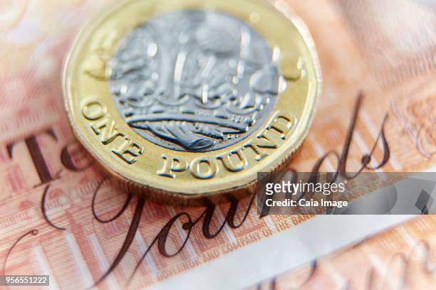 close up one pound coin on ten pound note - ten pound note stock pictures, royalty-free photos & images