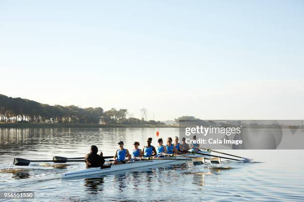 female rowers rowing scull on lake below blue sky - sculling crew stock pictures, royalty-free photos & images