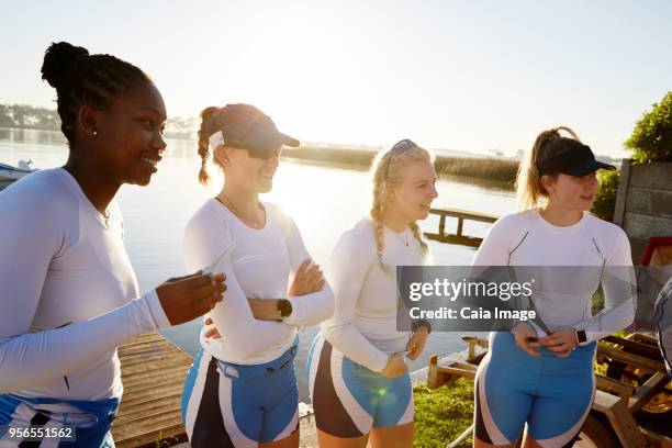 female rowing team standing at sunny lakeside - sculling crew stock pictures, royalty-free photos & images