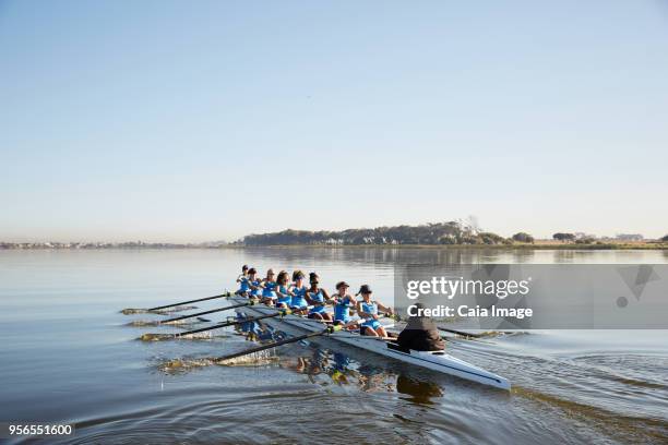 female rowing team rowing scull on tranquil lake - coxswain stock pictures, royalty-free photos & images