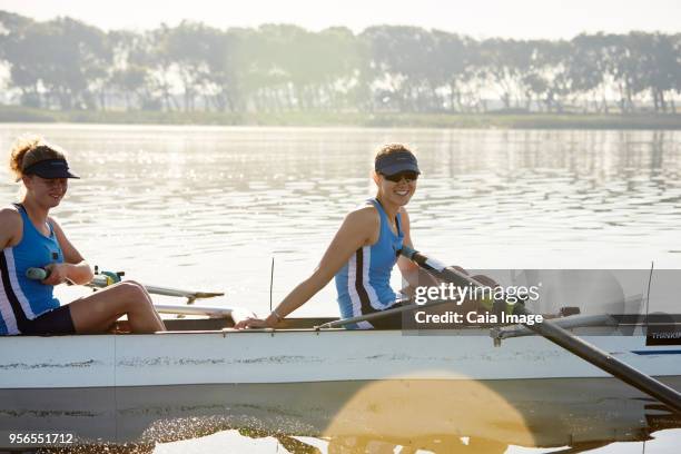 portrait smiling female rower in scull on sunny lake - sculling crew stock pictures, royalty-free photos & images