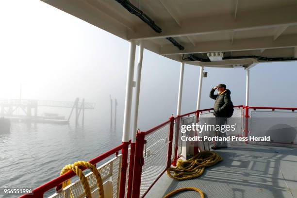 Paul Mulholland of Peaks Island shields his eyes from the sun on a foggy Tuesday morning on the deck of the Wabanaki ferry as it departs for Portland.