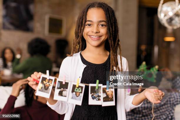 portrait smiling girl holding string of instant photos - black string photos et images de collection