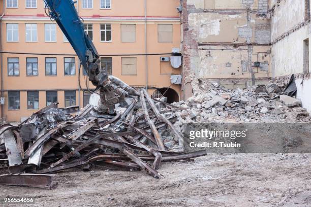 demolition truck in action. heap of rubble and a demolished building in the background - crash site stock pictures, royalty-free photos & images