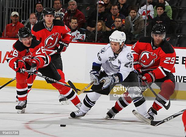 Martin St Louis of the Tampa Bay Lightning skates with the puck as Patrik Elias and Johnny Oduya of the New Jersey Devils chases during their game on...