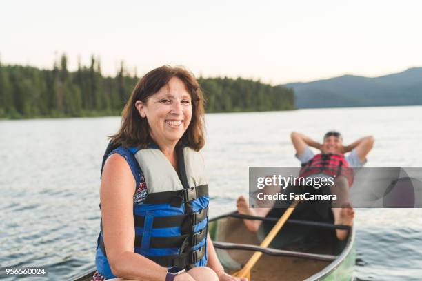 senior man lying down in a canoe on the lake - fat man lying down stock pictures, royalty-free photos & images