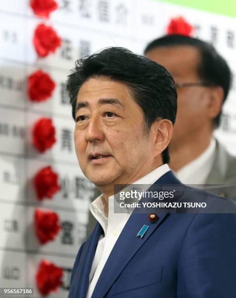 Japanese Prime Minister and ruling Liberal Democratic Party president Shinzo Abe smiles after he pin a rosette on his party's candidates list in the...