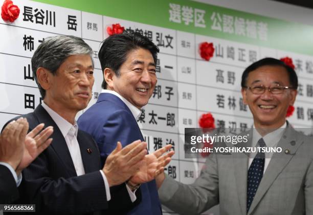 Japanese Prime Minister and ruling Liberal Democratic Party president Shinzo Abe and Secretary Genewral Sadakazu Tanigaki pin a rosette on their...