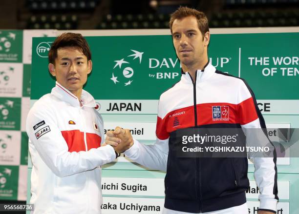Japan's Yoshihito Nishioka shakes hands with Richard Gasquet of France as they attend a drawing event of the Davis Cup World Group first round tennis...