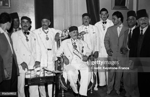 Le Prince Sadok Bey sur le trône tunisien entouré de ses fils et amis après son investiture le 5 juillet 1953 à Tunis, Tunisie.