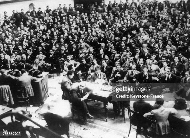 Vue générale de la salle du théâtre Auguste où se déroule le premier meeting fasciste, Mussolini est assis à une table au centre, le visage tourné...