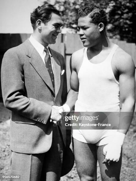 Le boxeur allemand Max Schmeling serre la main au boxeur noir américain Joe Louis lors de l'entraînement de ce dernier le 9 août 1936 à Pompton...