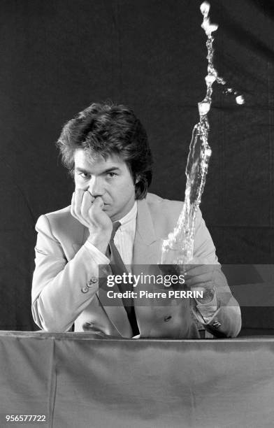 Daniel Guichard joue avec un verre d'eau en février 1982 à Paris, France.