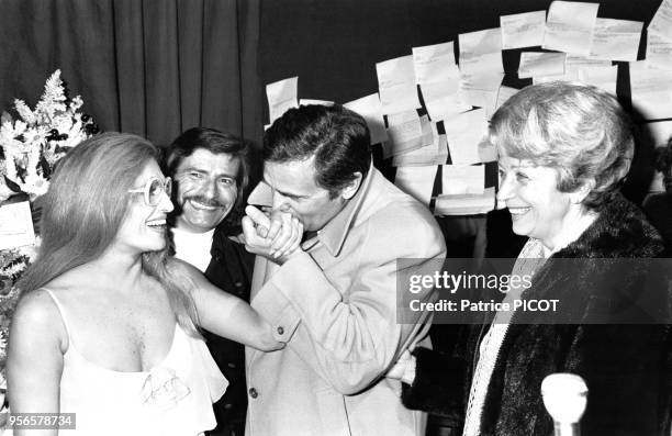 Portrait de la chanteuse Dalida se faisant baiser la main par l'acteur Roger Hanin en compagnie de son épouse Christine Gouze-Rénal le 6 janvier 1977.