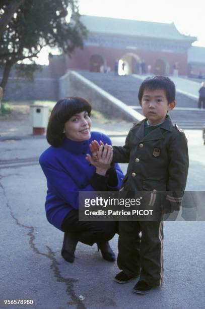 Mireille Mathieu avec un enfant en uniforme militaire à Pékin le 12 mai 1986.