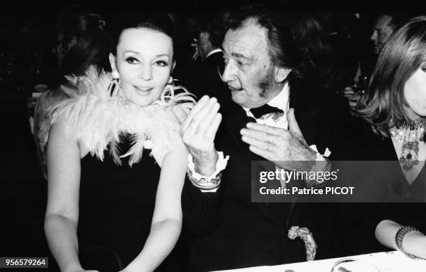 Portrait de Ludmila Tcherina et de Salvador Dali à table lors de la première du numéro 'Moulin Rouge' le 9 avril 1970 à Paris, France.