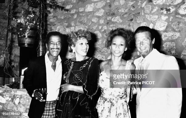 Les acteurs Sammy Davis Junior et Roger Moore accompagnés de leurs femmes assistent à la soirée Piaget le 8 août 1983 à Monaco.