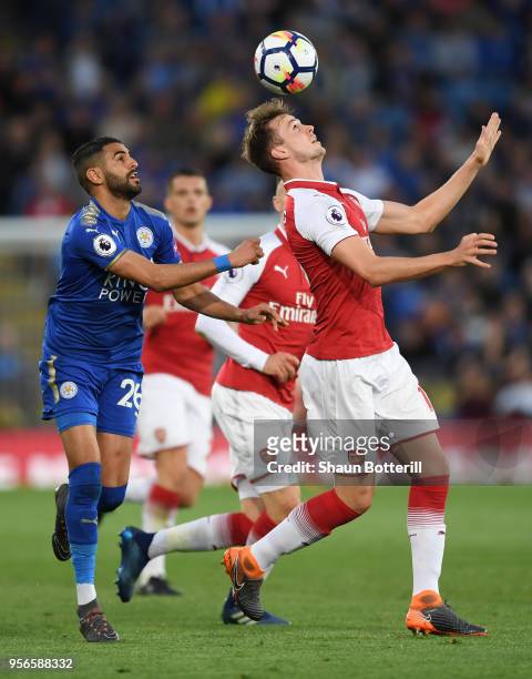 Rob Holding of Arsenal controls the ball with his head while under pressure from Riyad Mahrez of Leicester City during the Premier League match...