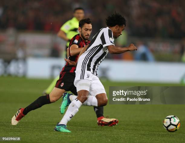 Juan Cuadrado of Juventus competes for the ball with Hakan Calhanoglu of AC Milan during the TIM Cup Final between Juventus and AC Milan at Stadio...