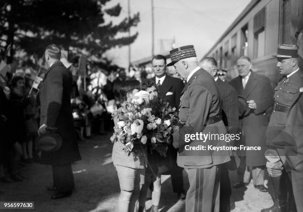 Sa descente de train, le maréchal Pétain reçoit un bouquet de fleurs des mains de deux garçons, à Grenoble, France en mars 1941.