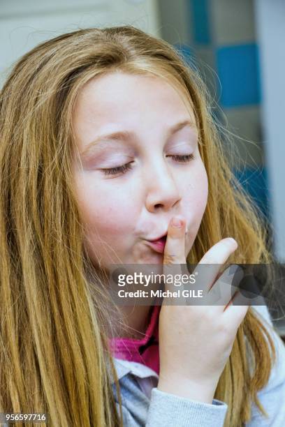 Portrait d'une fillette de sept ans faisant 'chut' pour demander le silence avec le doigt devant la bouche.