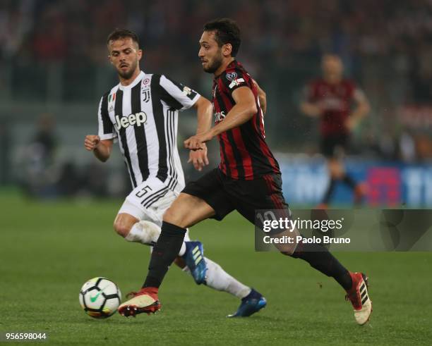 Miralem Pjanic of Juventus competes for the ball with Hakan Calhanoglu of AC Milan during the TIM Cup Final between Juventus and AC Milan at Stadio...