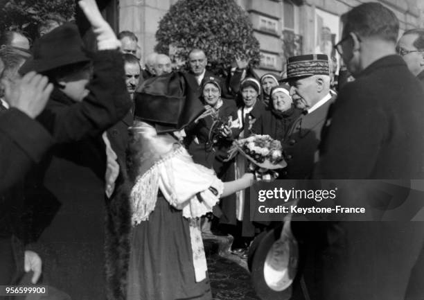 Le maréchal Pétain reçoit un bouquet de fleurs des mains d'une jeune fille vêtue su costume régional à son arrivée à Saint-Etienne, France en 1941.
