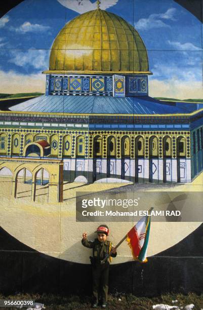 Enfant habillé en Pasdaran devant une peinture murale représentant la Mosquée al-Aqsa de Jérusalem en 1985 à Téhéran, Iran.