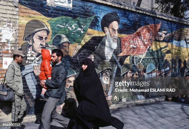 Famille passant devant une peinture murale à la gloire de la révolution islamique et de l'ayatollah Rouhollah Khomeini en février 1987 à Téhéran en...