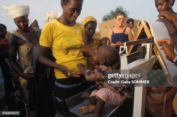 Mère pesant son enfant en 1981 en Haute Volta au Burkina Faso.