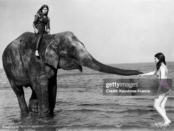 Deux jeunes filles travaillant au zoo de Cleethorpes donnent un bain dans la mer à une éléphante, à Cleethorpes, Royaume-Uni le 3 juillet 1968.