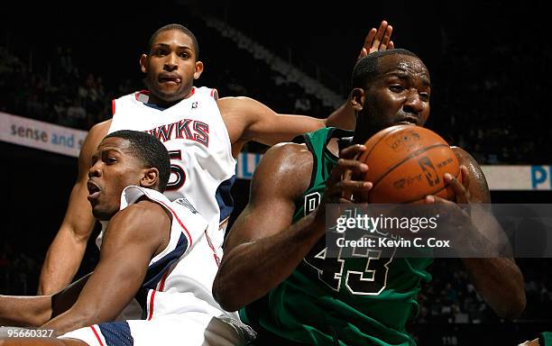 Kendrick Perkins of the Boston Celtics grabs a rebound against Joe Johnson and Al Horford of the Atlanta Hawks at Philips Arena on January 8, 2010 in...